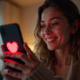 Jeune femme souriante avec smartphone et emoji cœur